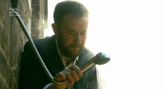 Image of Alex Horne performing the function of Roisin Conaty’s shower head holder. Image of Alex Horne performing the function of Roisin Conaty’s shower head holder.