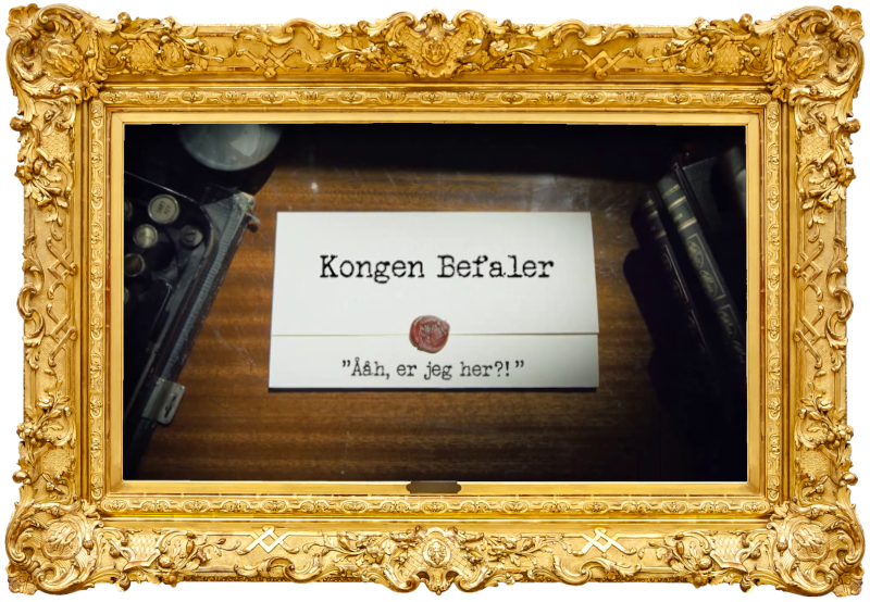 Image of the title card at the start of this episode, showing a task brief with the show title, 'Kongen Befaler', and the episode title, 'Ååh er jeg her?!' ['Oh, I'm here?!'], on a wooden desk. At the edges of the image, part of a typewriter keyboard and a stack of leather-bound books can be seen.