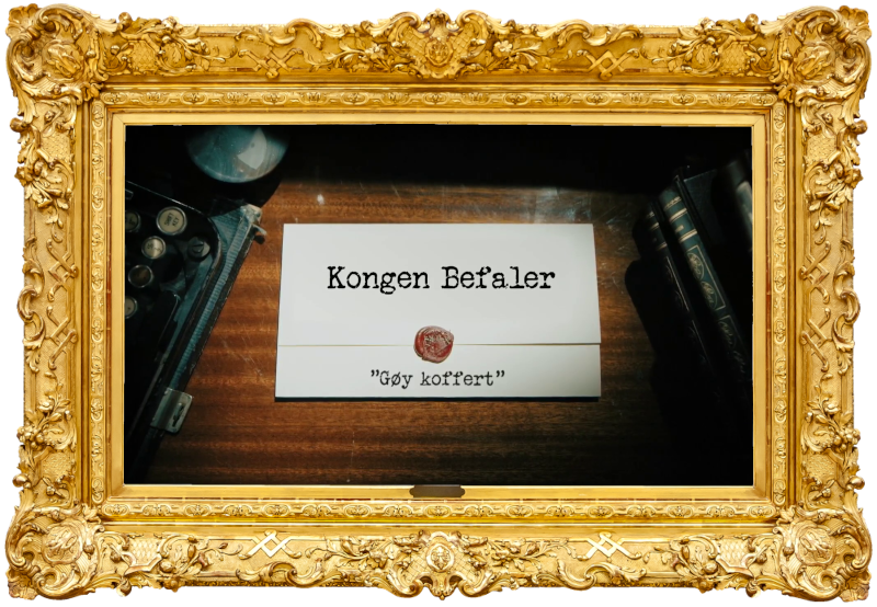 Image of the title card at the start of this episode, showing a task brief with the show title, 'Kongen Befaler', and the episode title, 'Gøy koffert' ['Fun suitcase'], on a wooden desk. At the edges of the image, part of a typewriter keyboard and a stack of leather-bound books can be seen.