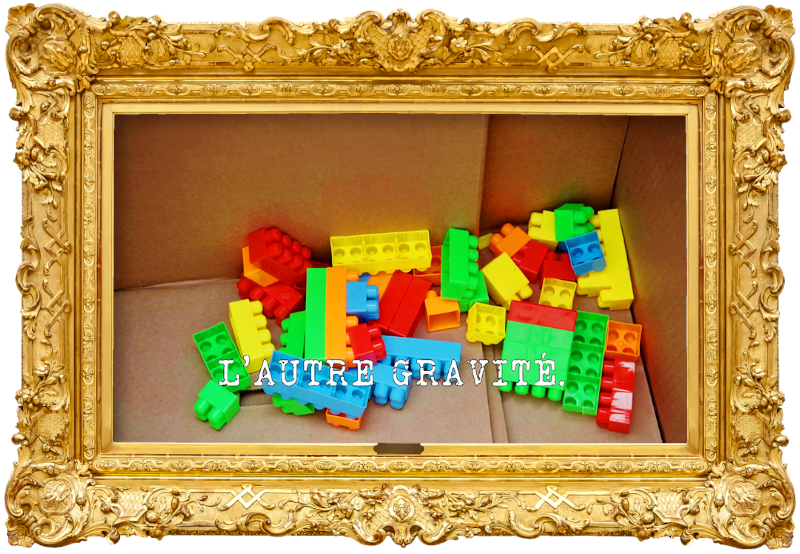 Image of some Duplo bricks in a cardboard box (a reference to the 'Get the most eggs into a frying pan' task, from the previous episode), with the episode title, 'L'autre gravité' ['The other gravity'], superimposed on it.