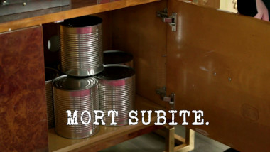 Image of a stack of large label-free tin cans inside a cabinet (a reference to the ‘Raise the water level to the top of the fish tank’ task), with the episode title 'Mort subite' ['Sudden death'] superimposed on it.