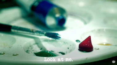 Image of an artist's palette, with a tube of blue paint, a paintbrush, and a blob of red paint (presumably taken during - or a reference to - the 'Paint a portrait of the Taskmaster without touching the red mat' task), with the episode title, 'Look at me', superimposed on it.