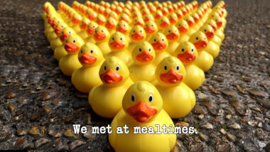 Image of a densely-packed triangle of rubber ducks on a concrete surface (taken during the 'Knock over the ducks without leaving the carpet' task), with the episode title, 'We met at mealtimes', superimposed on it.