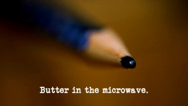 Image of the tip of a pencil (presumably a reference to the 'Draw a portrait of the Taskmaster across a flipchart' task), with the episode title, 'Butter in the microwave', superimposed on it.