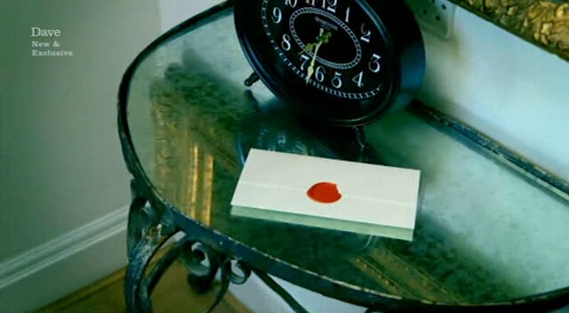 Sealed task brief sitting next to a black alarm clock on a glass end-table. Sealed task brief sitting next to a black alarm clock on a glass end-table.