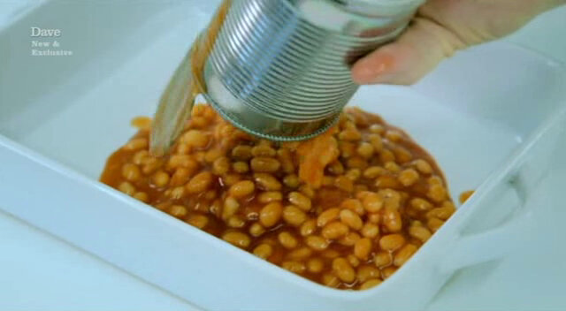 Image of a tin of baked beans being poured into a ceramic baking dish. Image of a tin of baked beans being poured into a ceramic baking dish.