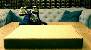 Pizza box sitting on the living room table next to an old-fashioned rotary phone.