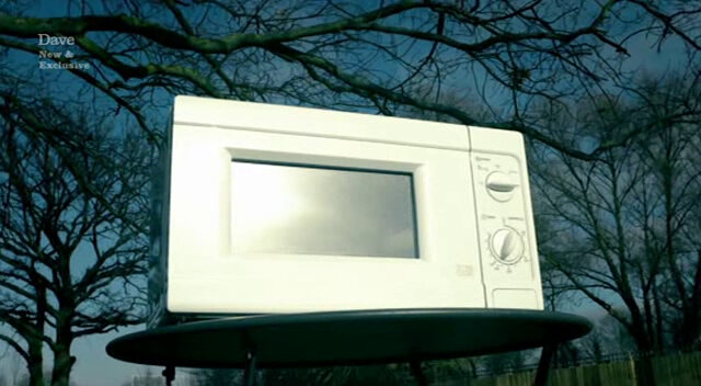 Microwave on a table outdoors with trees in the background. Microwave on a table outdoors with trees in the background.