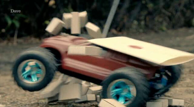 A remote controlled car carrying a sealed task brief crashes through a block tower. A remote controlled car carrying a sealed task brief crashes through a block tower.