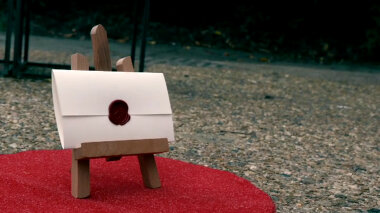 A sealed task brief resting on an appropriately sized easel stood on a small circle of red carpet in the driveway.