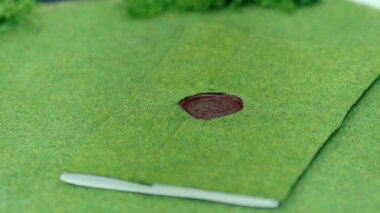 A sealed task covered with green felt blending in on a field of green felt.