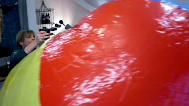 Mel Giedroyc attempts to inflate a giant beach ball.