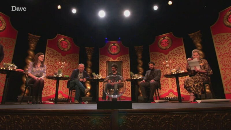 The cast of Taskmaster UK series 5 sits on stage looking at a fish bowl as Sally Phillips reads out the task. The cast of Taskmaster UK series 5 sits on stage looking at a fish bowl as Sally Phillips reads out the task.