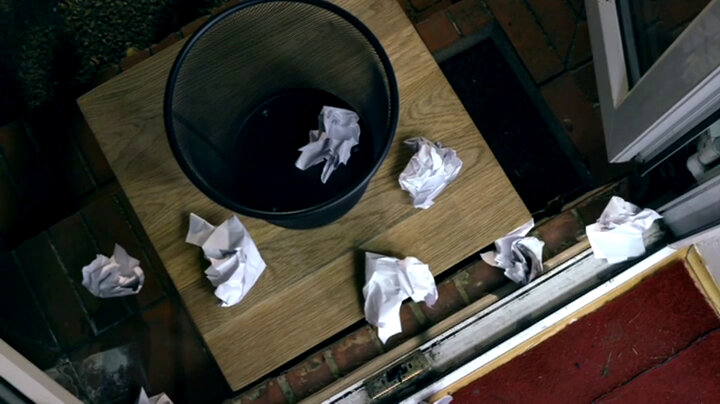 A crumpled piece of paper inside a wastebasket. Several more crumpled papers are on the floor surrounding the wastebasket. A crumpled piece of paper inside a wastebasket. Several more crumpled papers are on the floor surrounding the wastebasket.