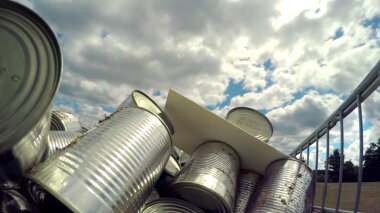 A sealed task brief resting on a jumbled pile of aluminium cans.