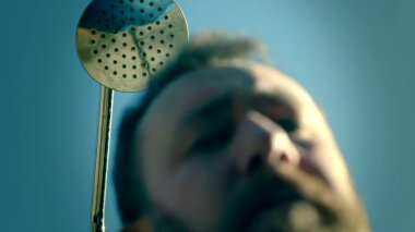 Alex Horne's face is out of focus in the foreground. The focus is on a showerhead in position above his head.
