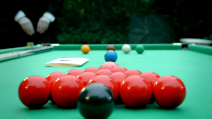 A sealed task brief on a snooker table. 21 snooker balls lie on the table. Alex Horne's hands are visible in the background clutching his clipboard. A sealed task brief on a snooker table. 21 snooker balls lie on the table. Alex Horne's hands are visible in the background clutching his clipboard.
