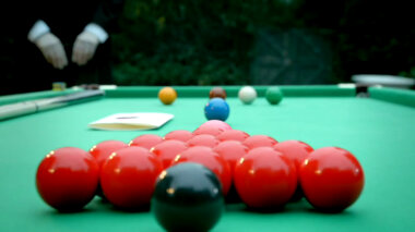 A sealed task brief on a snooker table. 21 snooker balls lie on the table. Alex Horne's hands are visible in the background clutching his clipboard.