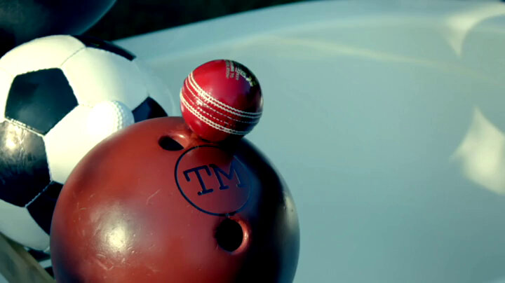 A football, bowling ball and cricket ball stacked together. The bowling ball is branded TM. A football, bowling ball and cricket ball stacked together. The bowling ball is branded TM.