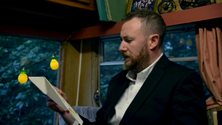 Alex Horne in the caravan reading a task. Alex Horne in the caravan reading a task.