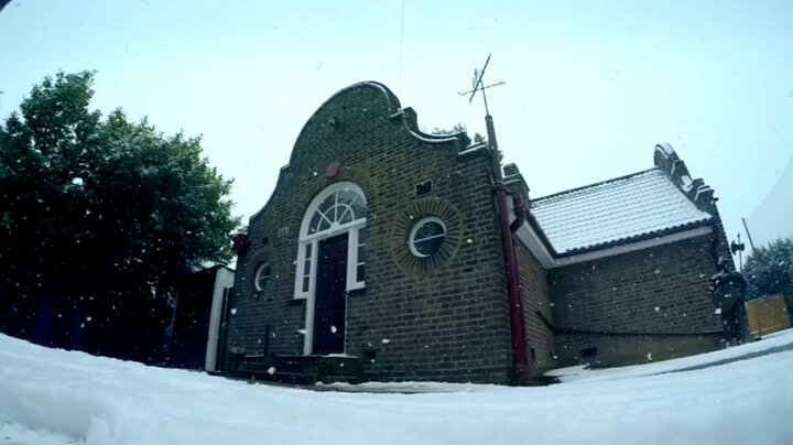 A low shot of the Taskmaster house. The ground and roof are covered in snow. A low shot of the Taskmaster house. The ground and roof are covered in snow.