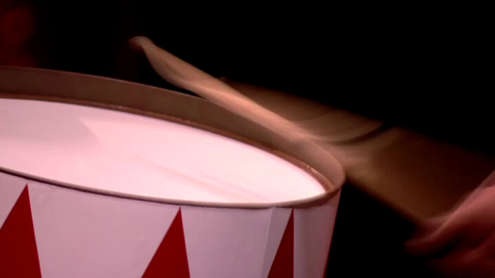 A close-up of a drum being struck. The hand of the drummer and the drumstick are out of focus due to motion. A close-up of a drum being struck. The hand of the drummer and the drumstick are out of focus due to motion.