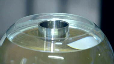A close-up of a glass bowl full of water. A small metal bowl floats in the water.
