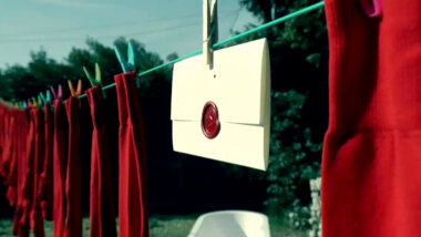 Many red socks hanging on a clothesline. Near the end is a hanging sealed task.