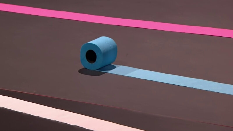 A partially unrolled blue toilet roll on the Taskmaster studio stage. Part of a pink and white unrolled toilet roll can also be seen.