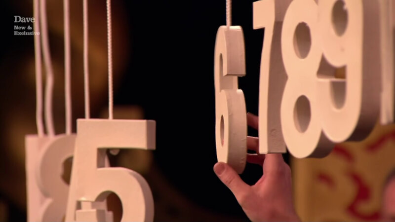 A sequence of white numbers hanging on string. The numbers 5, 6, 7, 8 and 9 are clearly seen. A hand is touching the number 6. A sequence of white numbers hanging on string. The numbers 5, 6, 7, 8 and 9 are clearly seen. A hand is touching the number 6.