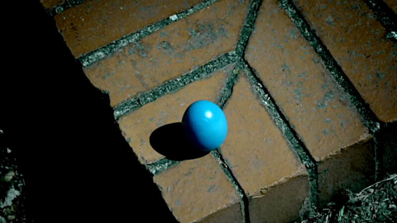 A close-up of a brown brick step. On the step is a blue egg. A close-up of a brown brick step. On the step is a blue egg.