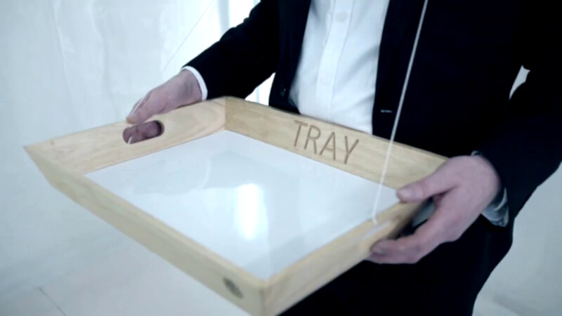 A wood and white plastic serving tray being carried by Alex Horne. On the side of the tray is the word 'tray'. A wood and white plastic serving tray being carried by Alex Horne. On the side of the tray is the word 'tray'.