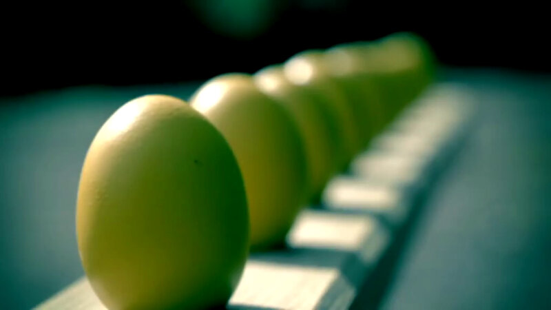 Ten dyed yellow eggs sitting in a row on a wooden board. Ten dyed yellow eggs sitting in a row on a wooden board.
