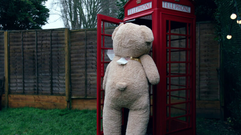 A very large (adult size) tan teddy bear being pulled into a red phone box. You can only see the bear from behind. A very large (adult size) tan teddy bear being pulled into a red phone box. You can only see the bear from behind.
