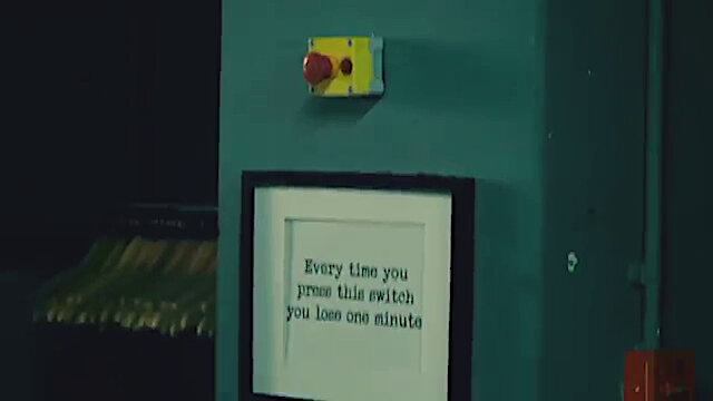 Part of a grey green wall. On the wall is red button on a yellow box. Below that is a white sign in a black frame. The sign reads 'Every time you press this switch you lose one minute.' Part of a grey green wall. On the wall is red button on a yellow box. Below that is a white sign in a black frame. The sign reads 'Every time you press this switch you lose one minute.'