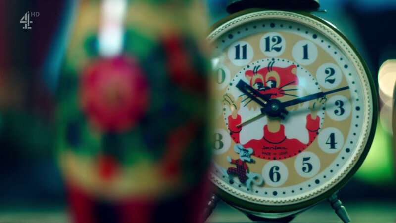 A wind-up alarm clock with stylized red cat on the face. The second hand is a mouse. In front of the clock is an out-of-focus Russian nesting doll. A wind-up alarm clock with stylized red cat on the face. The second hand is a mouse. In front of the clock is an out-of-focus Russian nesting doll.