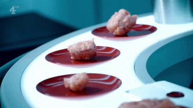 Four plates of batter-fried food on an aeroplane bar counter. A sealed task brief is also on the counter.