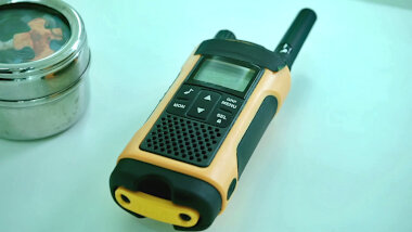 A walkie-talkie on the lab table next to a metal tin containing a jigsaw.
