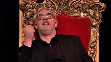 Greg Davies seated on his throne. His eyes are closed and his mouth is slightly open.