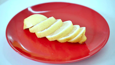 A lemon sliced into six pieces arranged on a red plate.