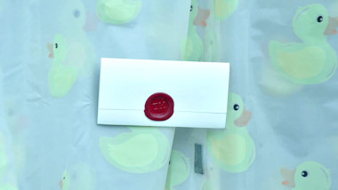 A sealed task brief stuck to a shower curtain with a repeating yellow rubber duck design.