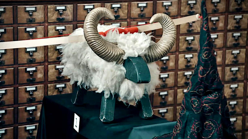 A wooden bow rests on top of a woolly toy ram. A wooden bow rests on top of a woolly toy ram.