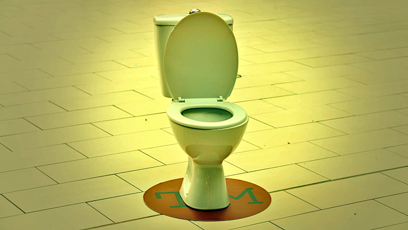 A toilet stands on a red circle in the middle of a vast tile floor. A toilet stands on a red circle in the middle of a vast tile floor.