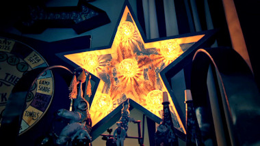 A decorative wooden star containing 6 lit bulbs glows in the dark living room. It's surrounded by circus ephemera.