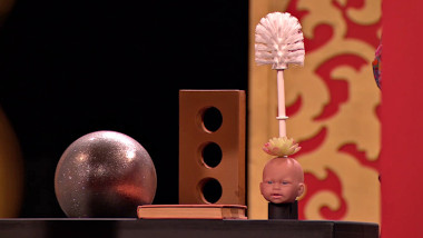 A ball, a brick, a book, a plastic succulent planter shaped like a baby's head, and a toilet brush.