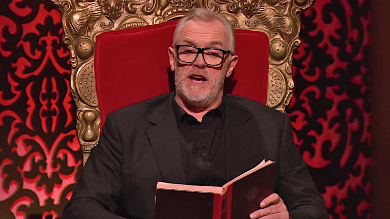 Greg Davies on his throne reads animatedly from a book. Greg Davies on his throne reads animatedly from a book.