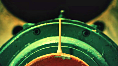 A golf tee resting on its head on a piece of metal equipment.