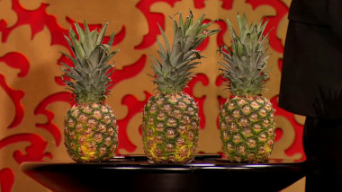 Three pineapples on a table.