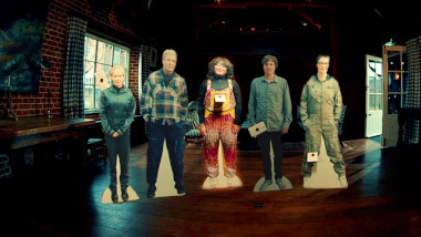 The cast of UK series 16 set up as cardboard cut-outs, lined up, each with a sealed task brief.
