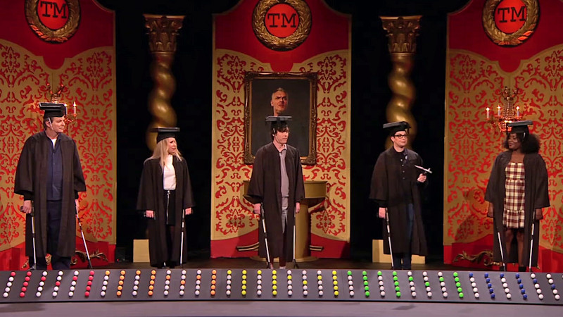 The cast of UK series 16 on the studio stage. They are wearing academic robes and hats and holding litter-pickers. The cast of UK series 16 on the studio stage. They are wearing academic robes and hats and holding litter-pickers.